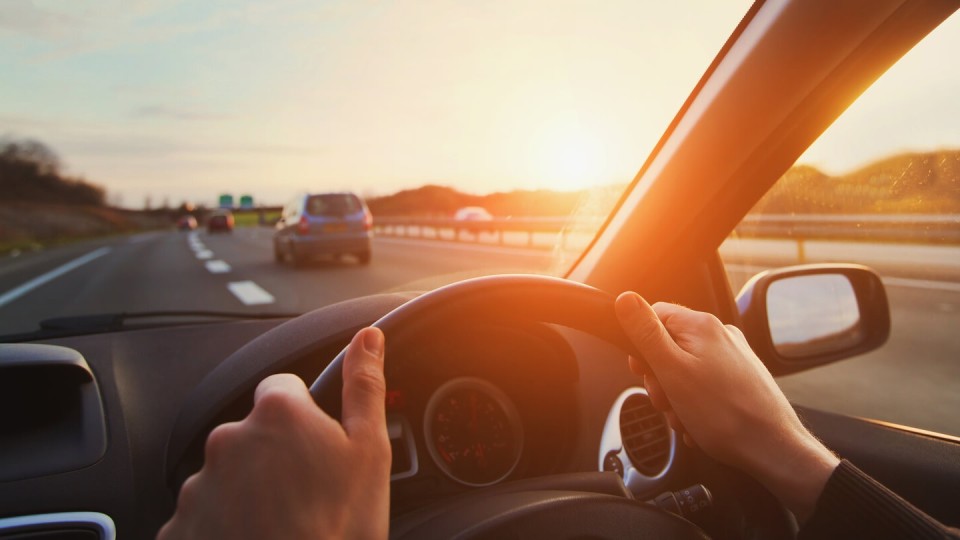 Hands on the wheel of a car driving along the motorway