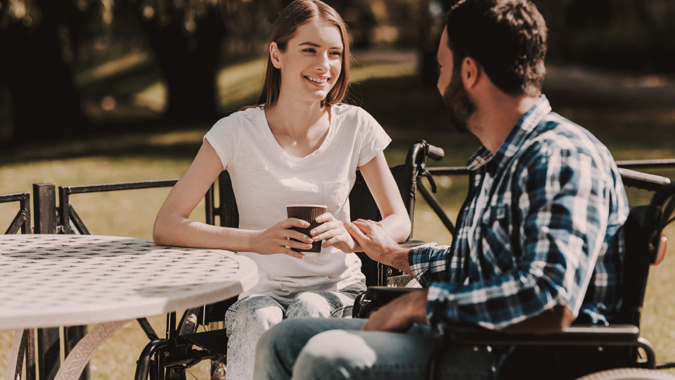 Man in wheelchair with woman drinking coffee