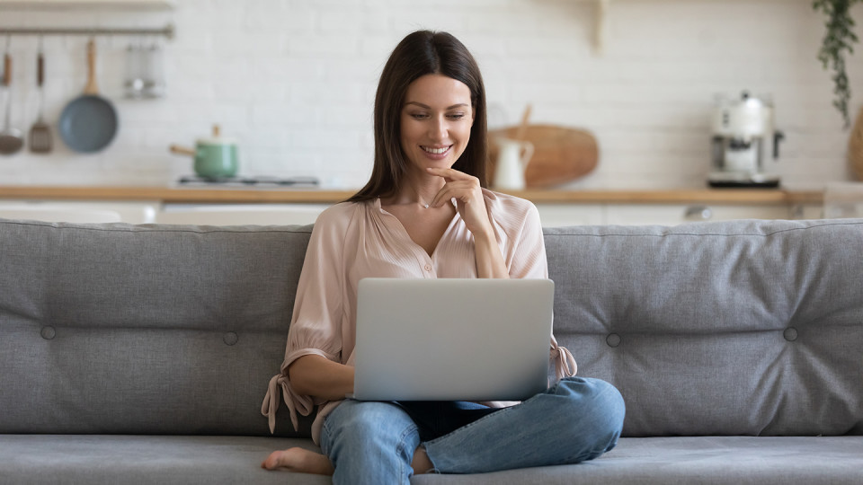 Woman smiling at laptop on couch